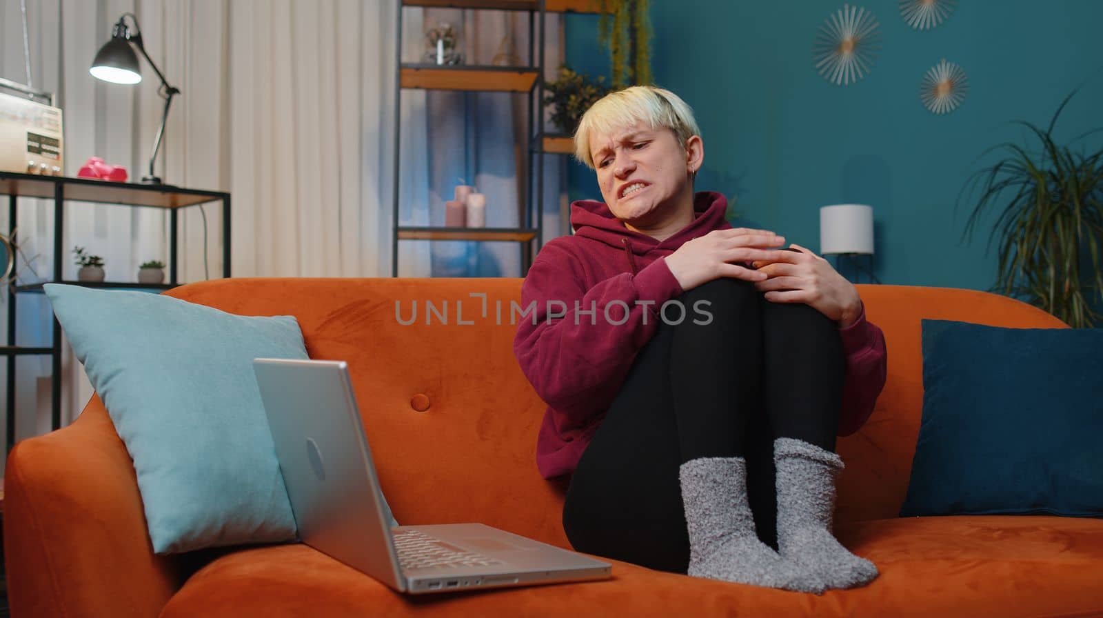Displeased woman with short blonde hair use laptop typing browsing working, loses becoming surprised sudden lottery results bad news, fortune loss fail. Adult girl at home in evening room on couch