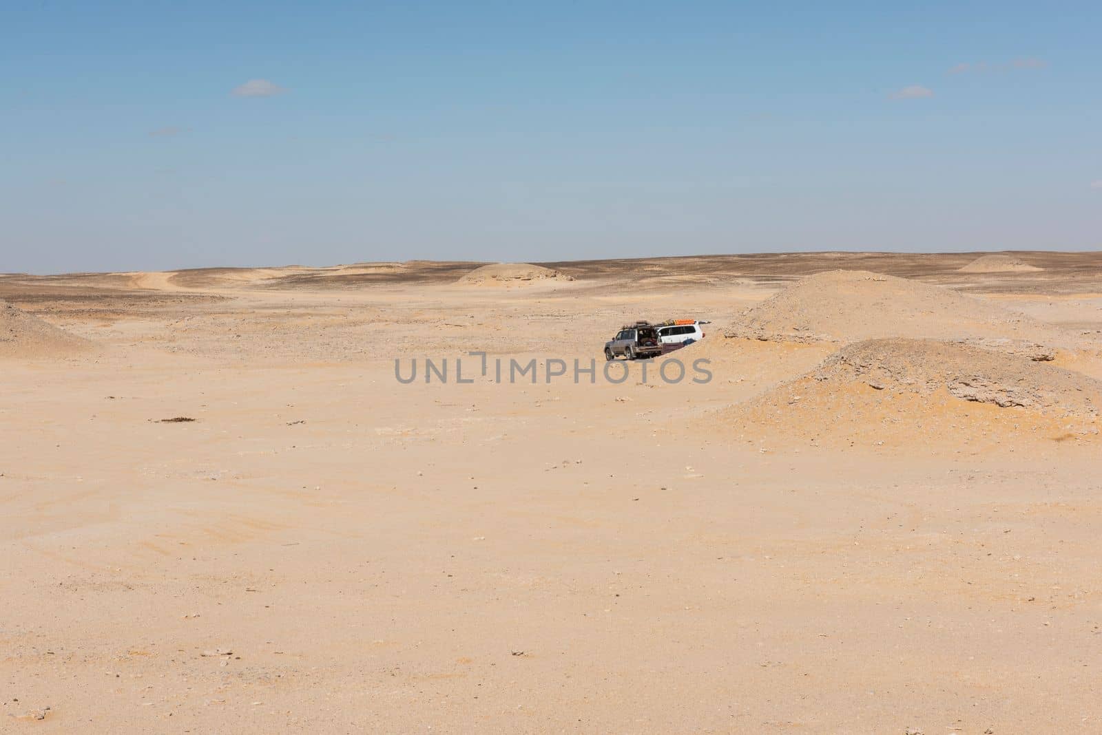 Landscape scenic view of desolate barren western desert in Egypt with rocky vista and off-road vehicle