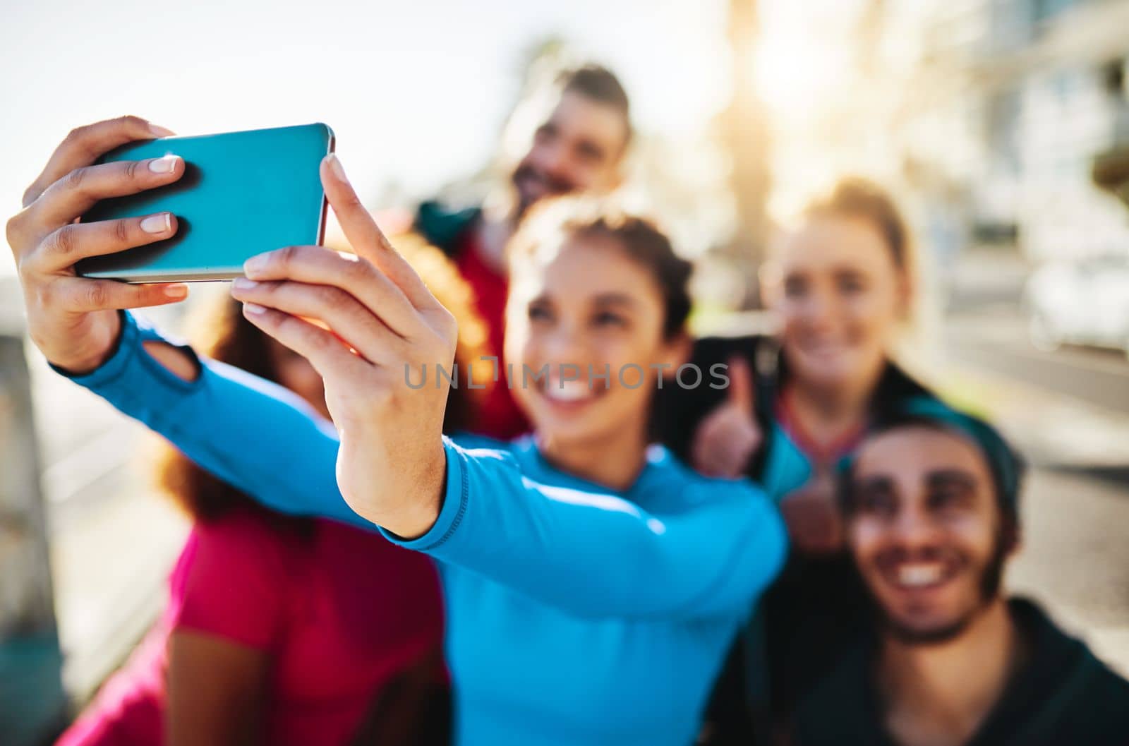 You get more than a workout when exercising with friends. a fitness group taking a selfie while out for a run on the promenade. by YuriArcurs