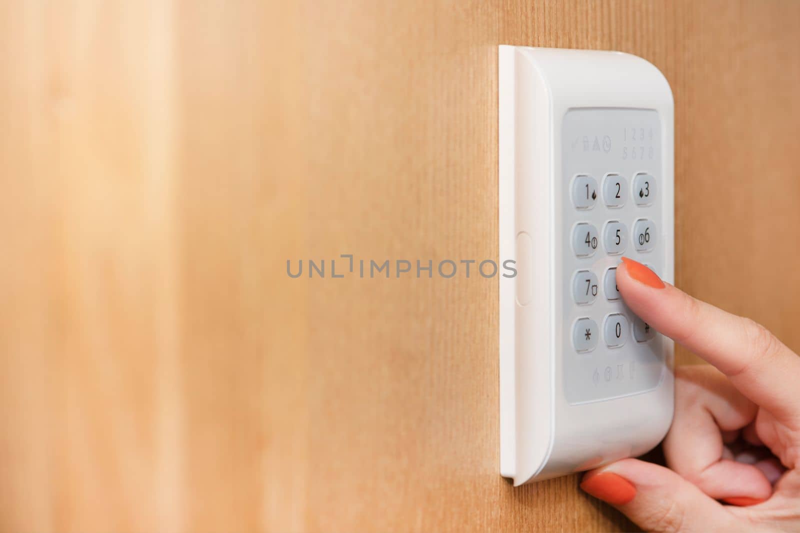 Alarm panel. The hand enters the code from the house security alarm. Real estate security, home security system. by SERSOL