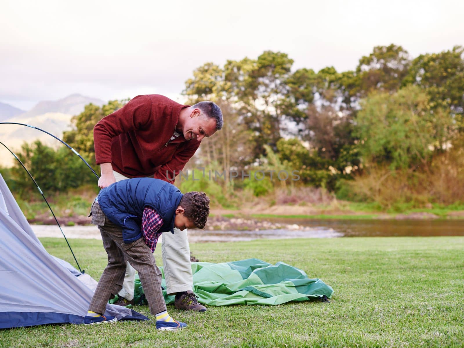 There you go. a father and son setting up a tent together while camping