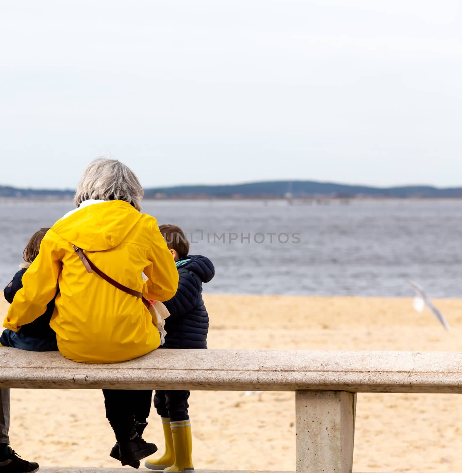 senior woman sitting on a bench by the beach by lhorintson