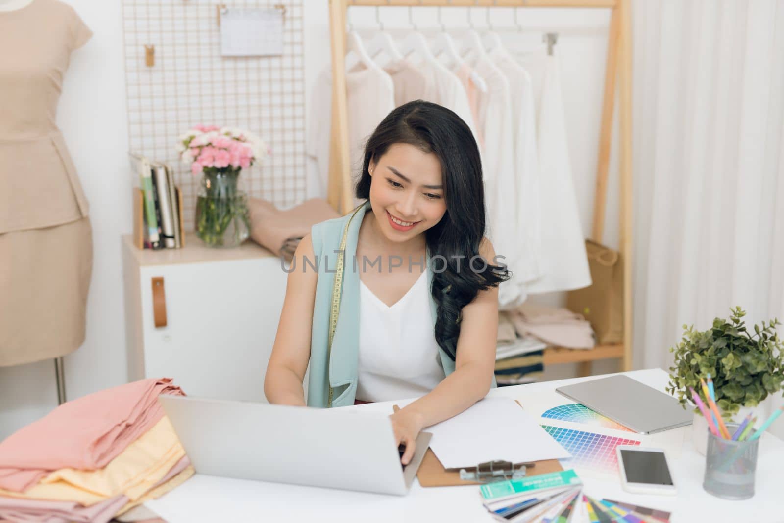 Portrait of a young Asian fashion designer working on her atelier