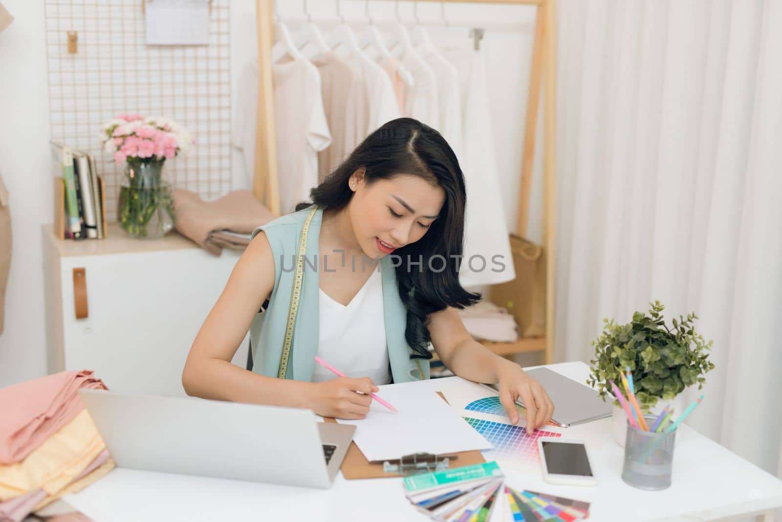 A young Asian fashion designer working on her atelier by makidotvn