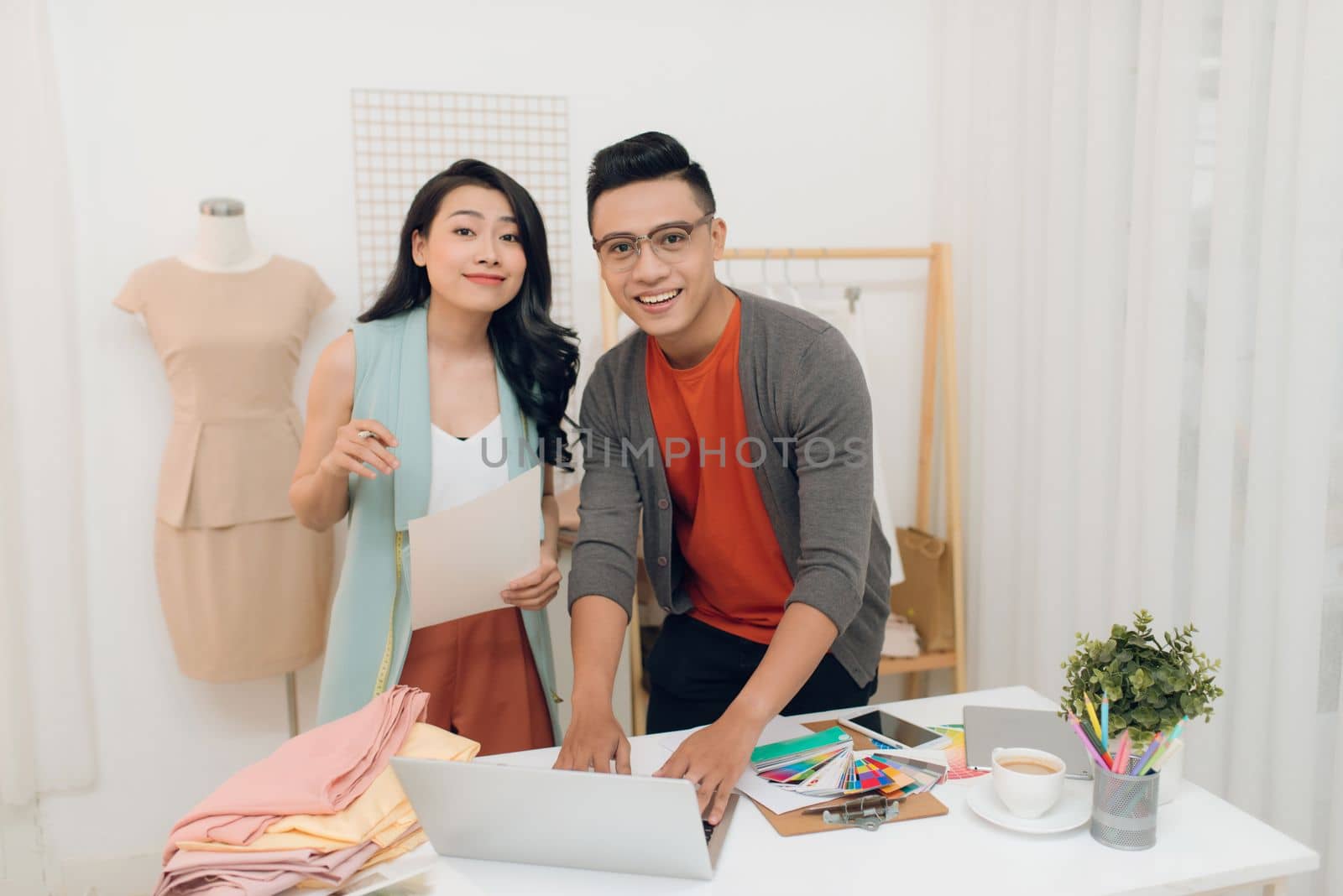Happy young woman and man fashion designer working in the workshop by makidotvn