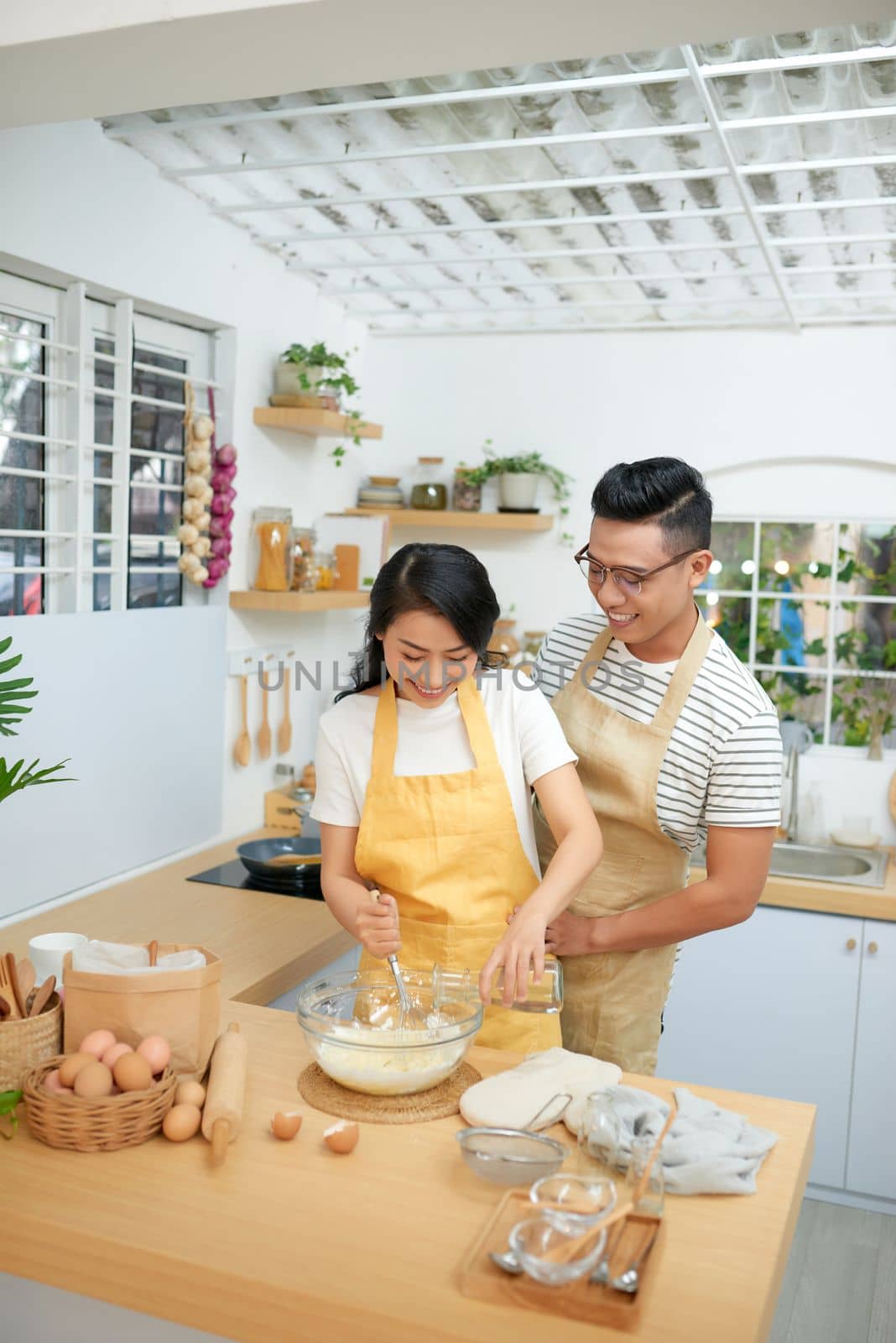 Couple man and woman wearing aprons having fun while making homemade pasta in kitchen at home by makidotvn