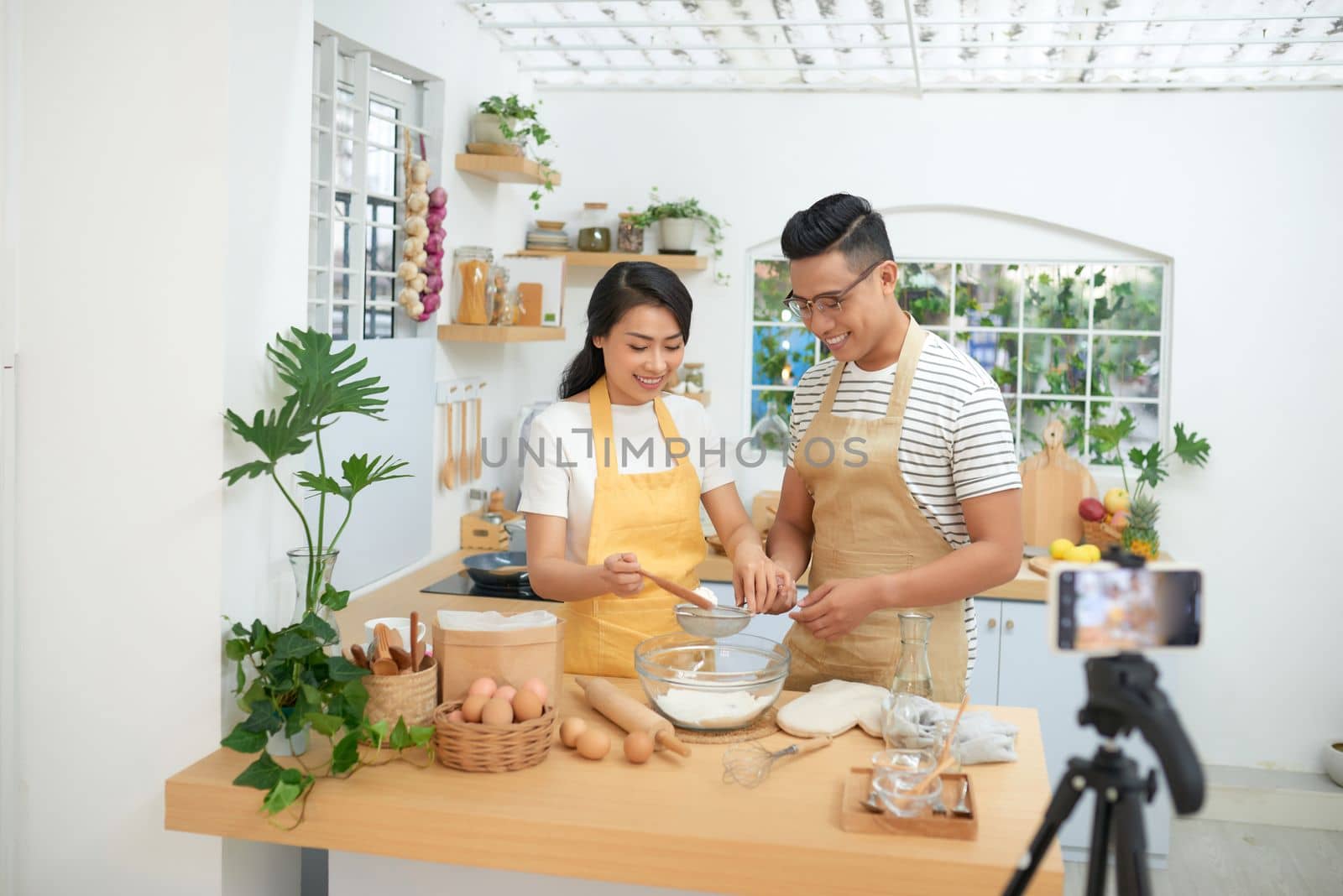 Young asian couple cooking together and recording live video for vlog and social media with professional camera by makidotvn