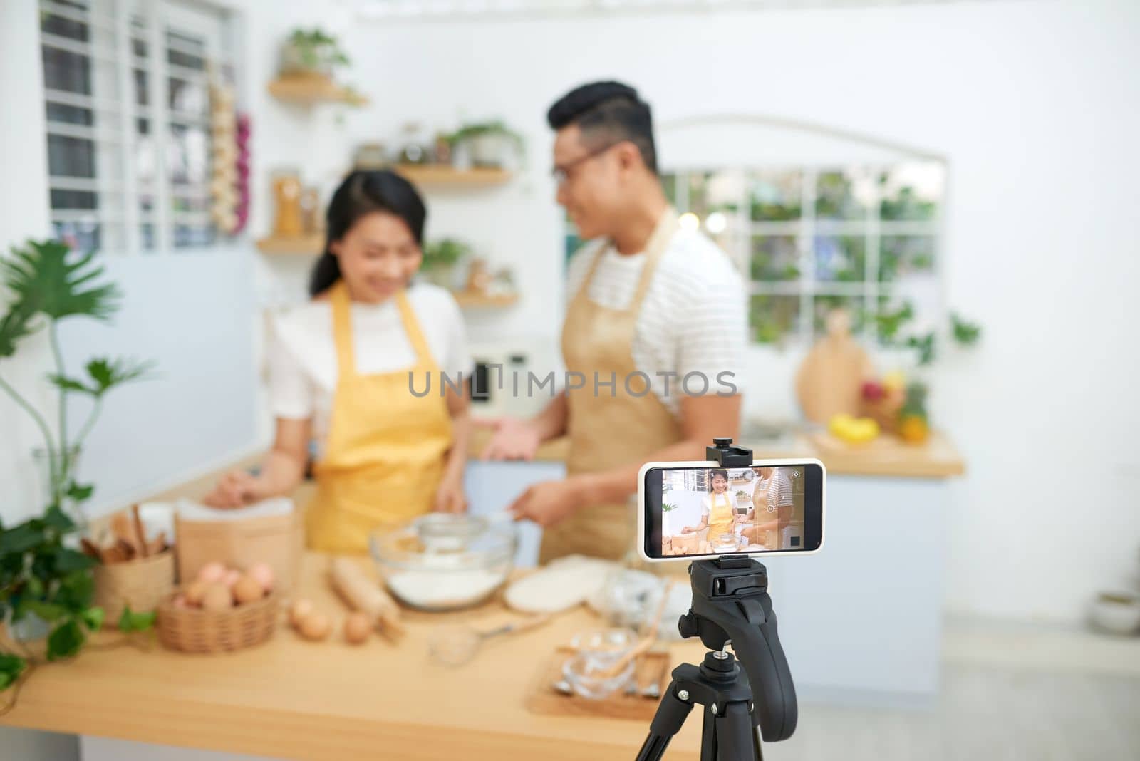 Young asian couple cooking together and recording live video for vlog and social media with professional camera by makidotvn
