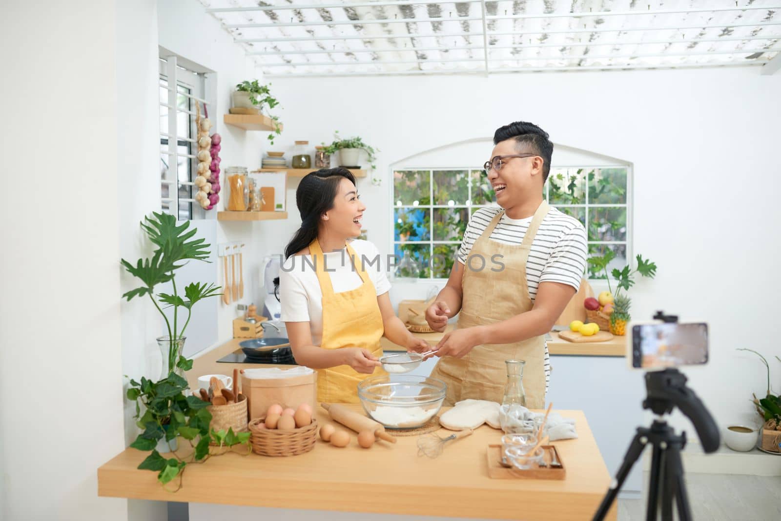 Young asian couple cooking together and recording live video for vlog and social media with professional camera by makidotvn