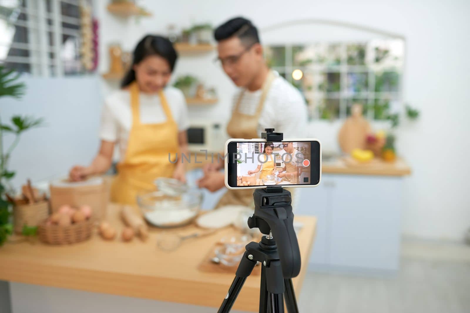 Young asian couple cooking together and recording live video for vlog and social media with professional camera