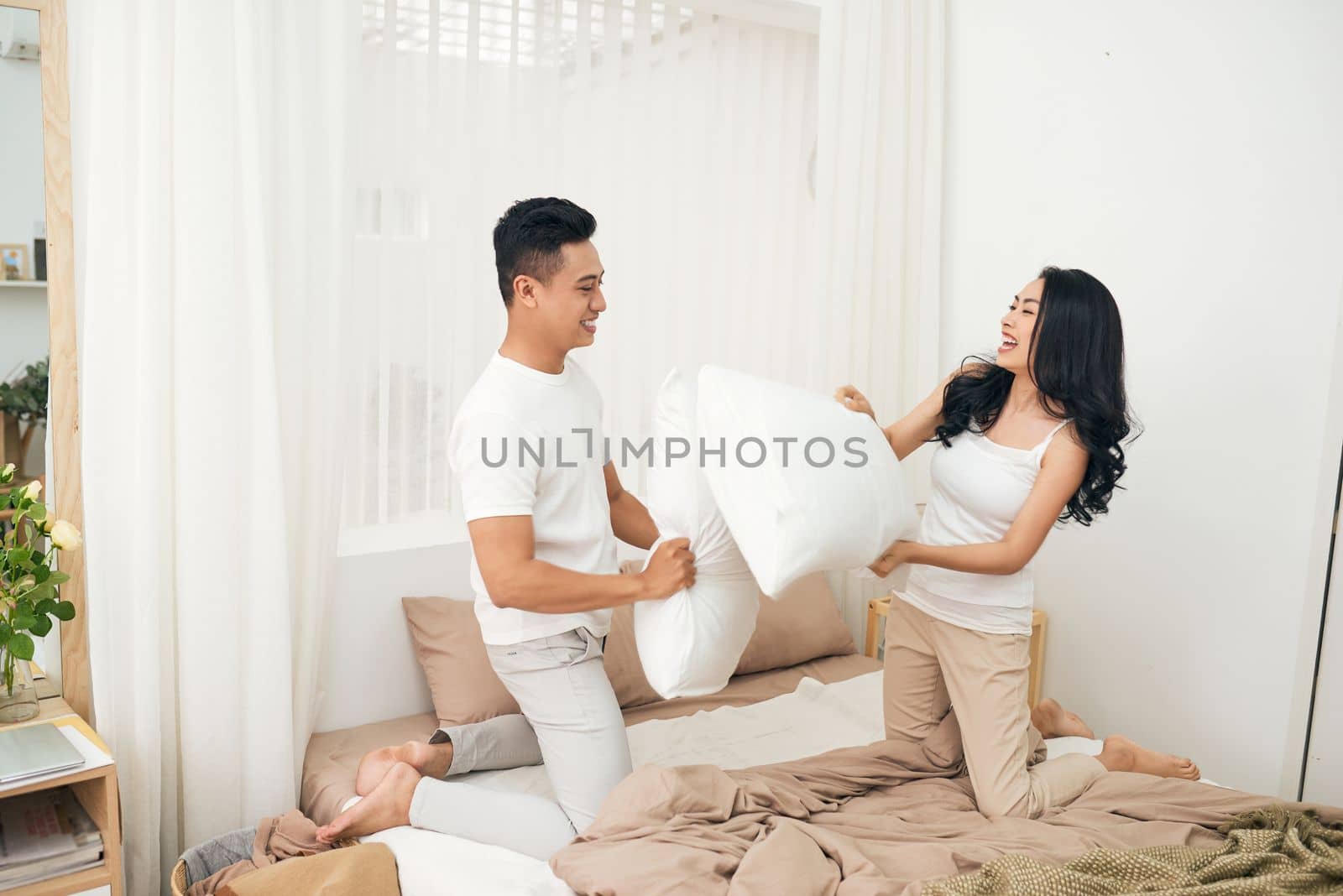 Picture showing happy couple having pillow fight by makidotvn