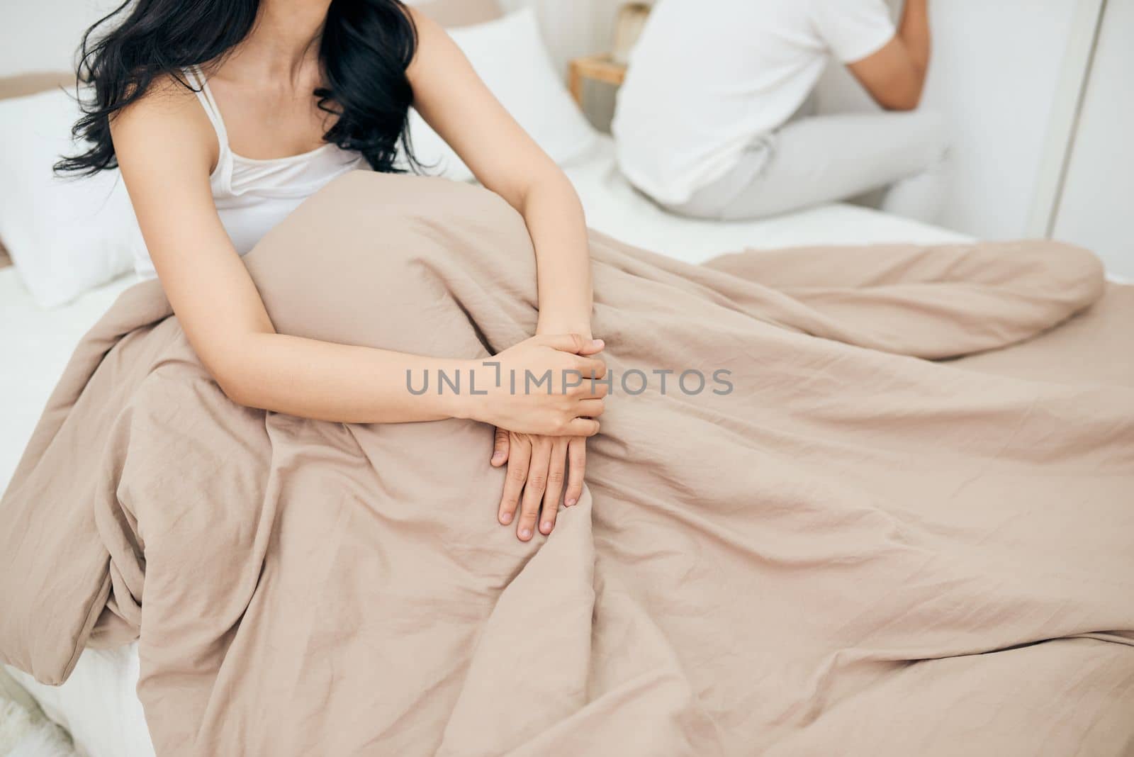 Unhappy Young Couple Sitting On Bed In Bedroom