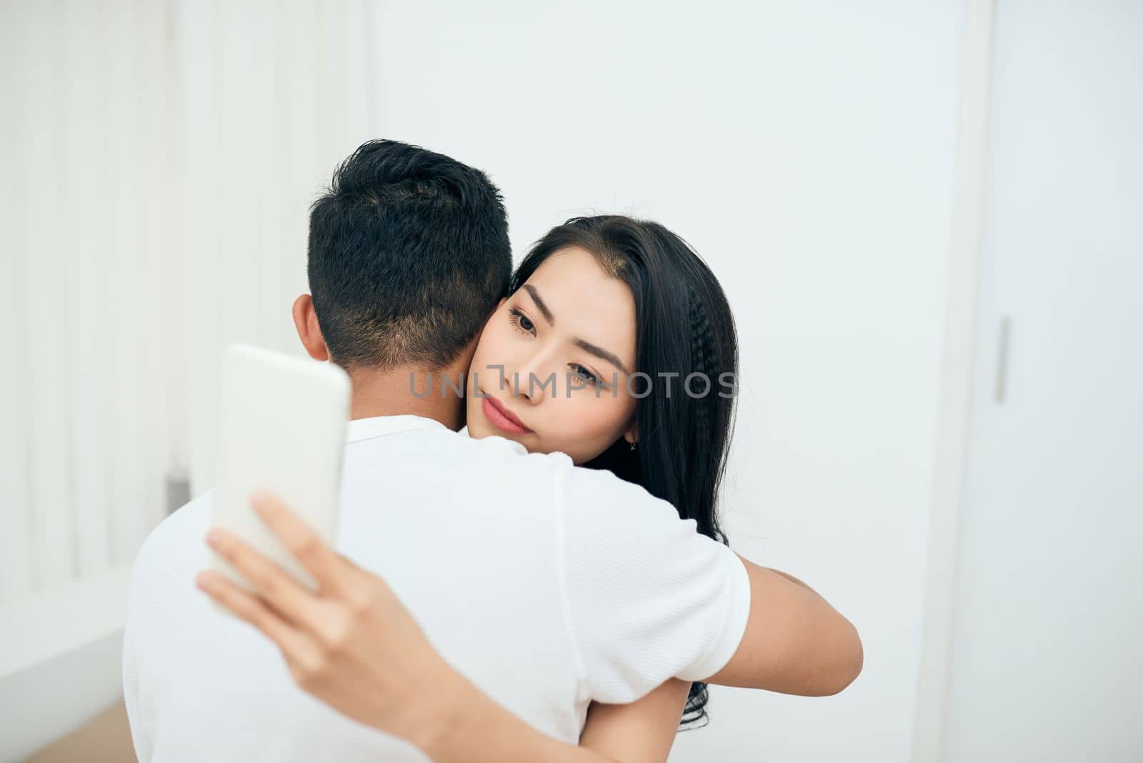 Young couple in the bedroom. An attractive woman is checking incoming messages in the morning by makidotvn