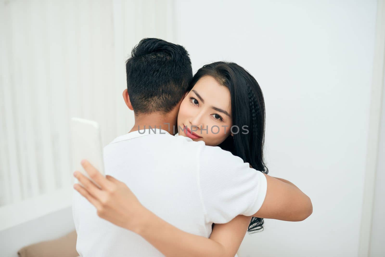 Young couple in the bedroom. An attractive woman is checking incoming messages in the morning