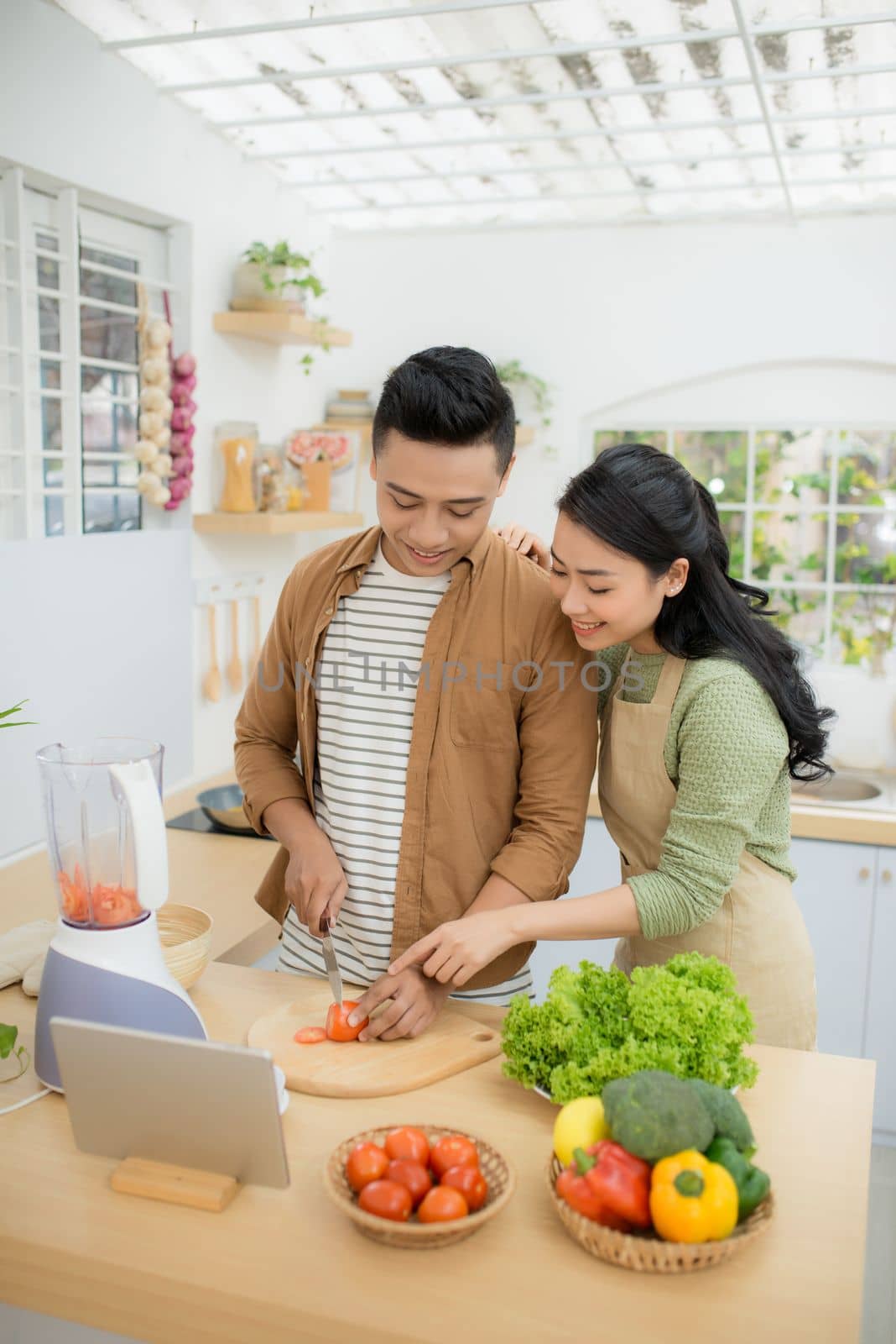 Portrait of a pretty young couple cooking together according to a recipe on a tablet computer