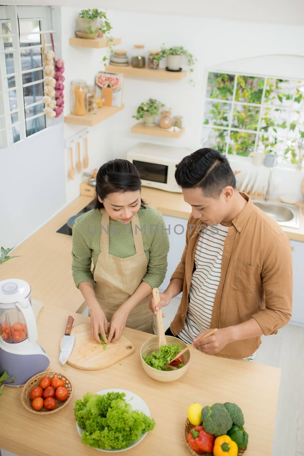 Loving joyful young couple embracing and cooking together, having fun in the kitchen by makidotvn