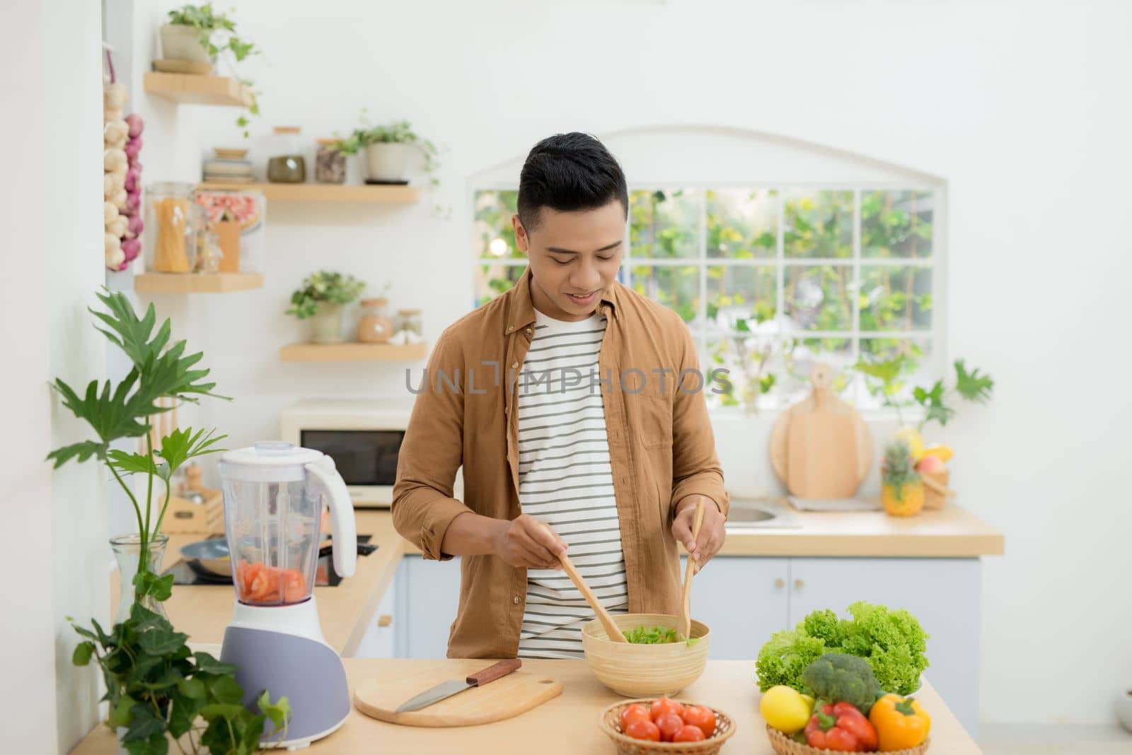 Young man preparing healthy vegetable salad by makidotvn