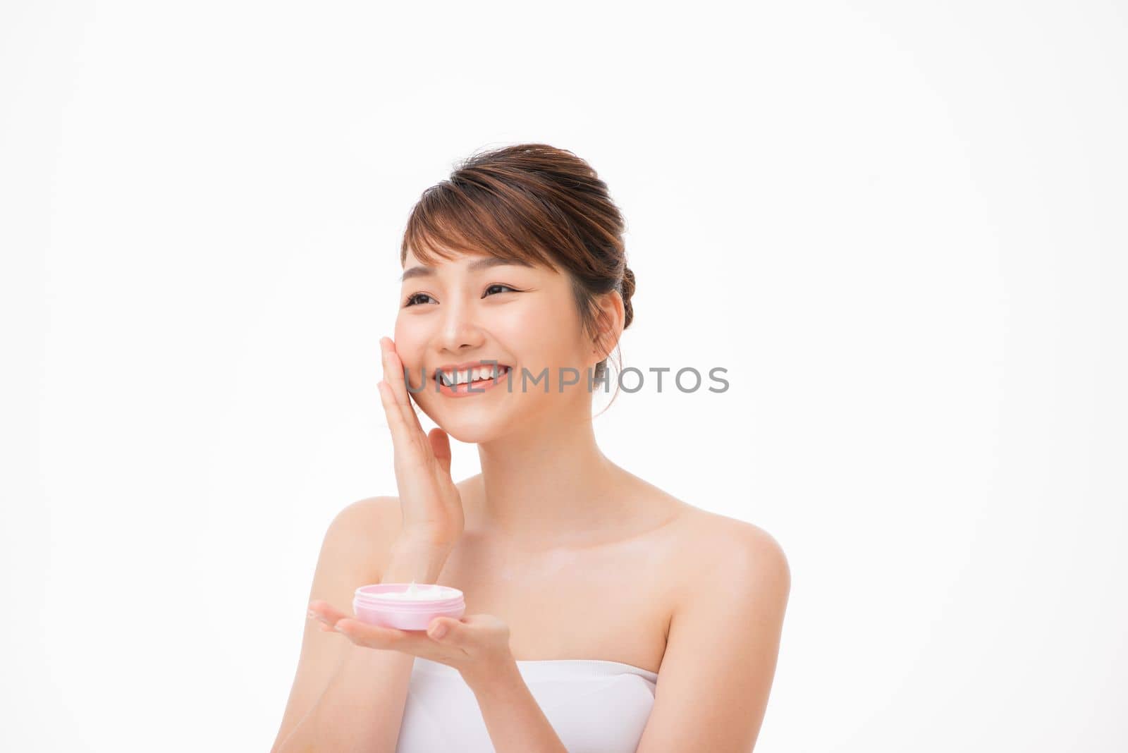 Beauty concept. Asian girl is applying cream on her face.