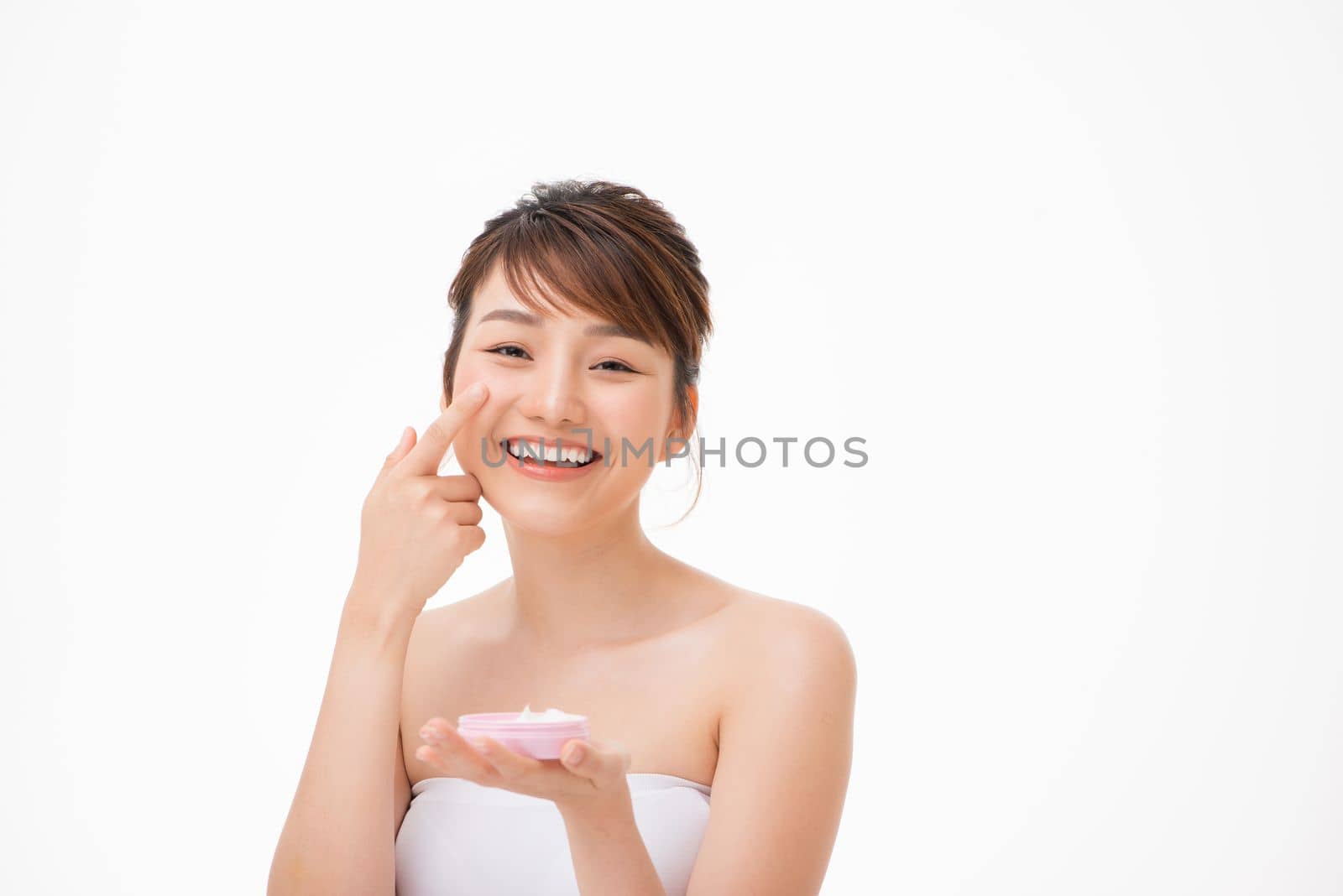 Beauty concept. Asian girl is applying cream on her face.
