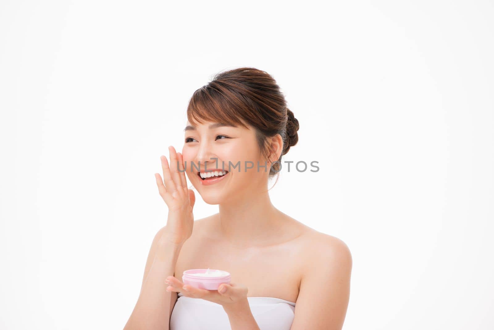 Beauty concept. Asian girl is applying cream on her face.