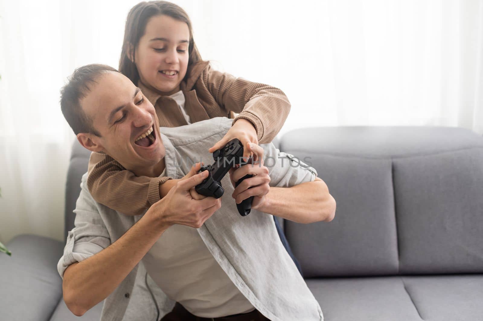 family, gaming and entertainment concept - happy father and little daughter with gamepads playing video game at home by Andelov13
