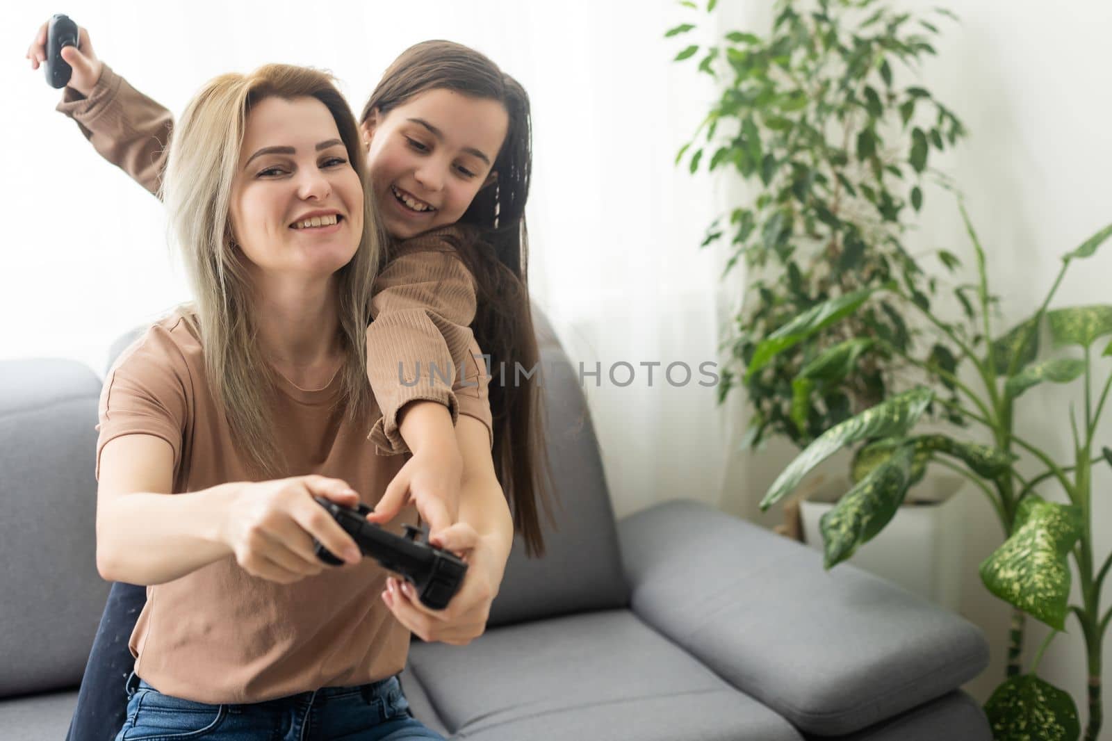 Mother and daughter playing video games on laptop at home. by Andelov13