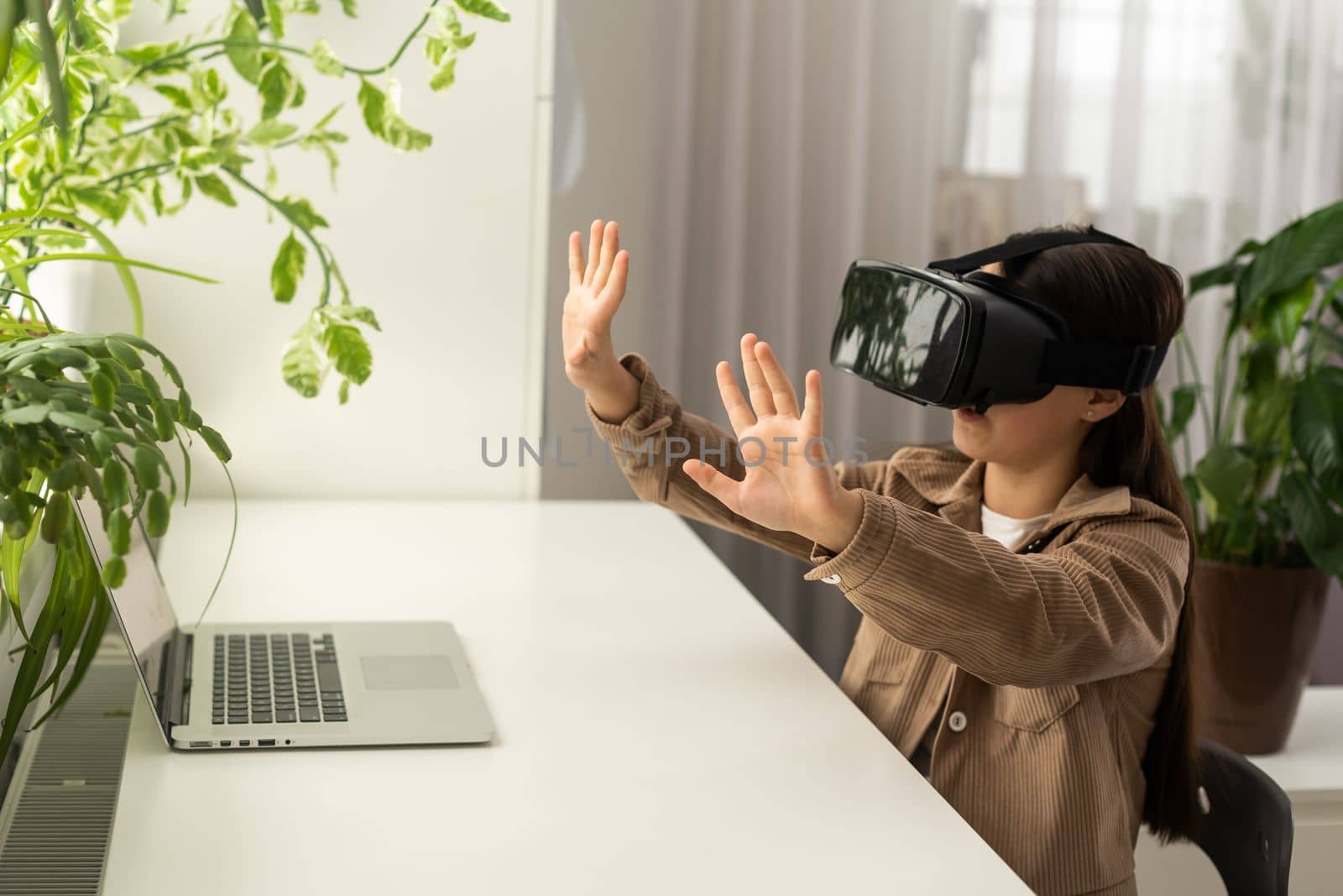 technology, augmented reality, entertainment and people concept - happy girl teenager in virtual headset or 3d glasses and headphones playing game at home