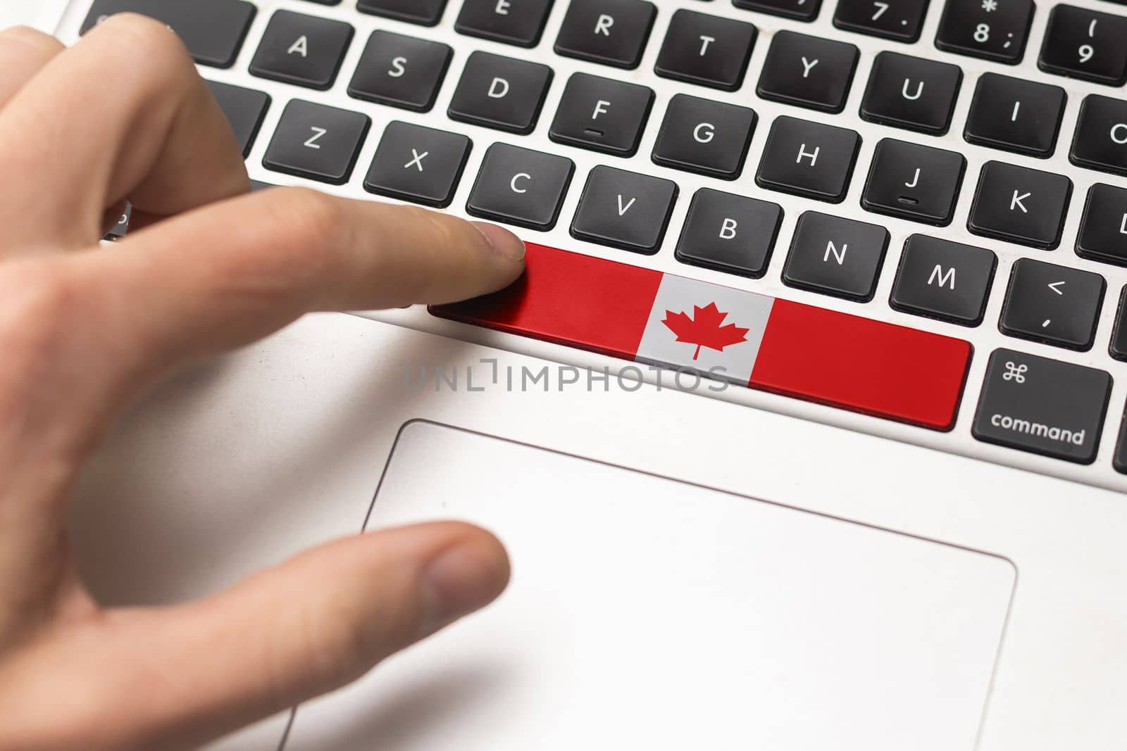 Computer key with the Canada on it. Male hand pressing computer key with Canada flag. by Andelov13