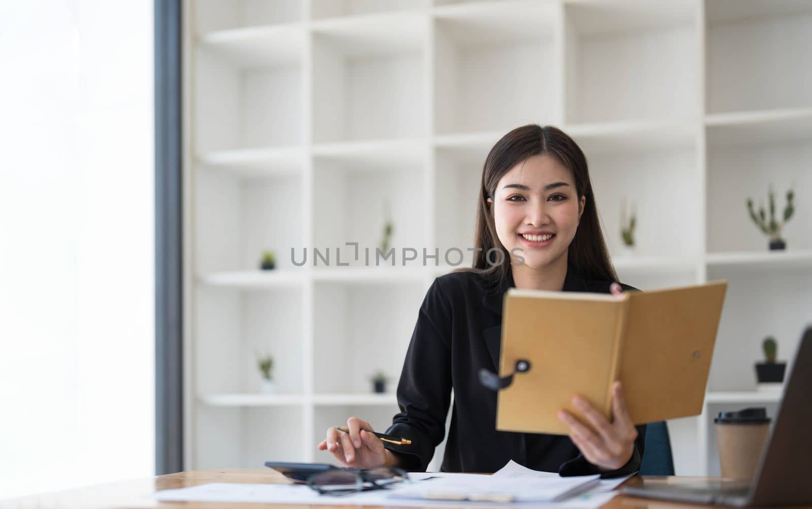 Asian businesswoman meeting at the office, taking notes and using a tablet at the office. by wichayada