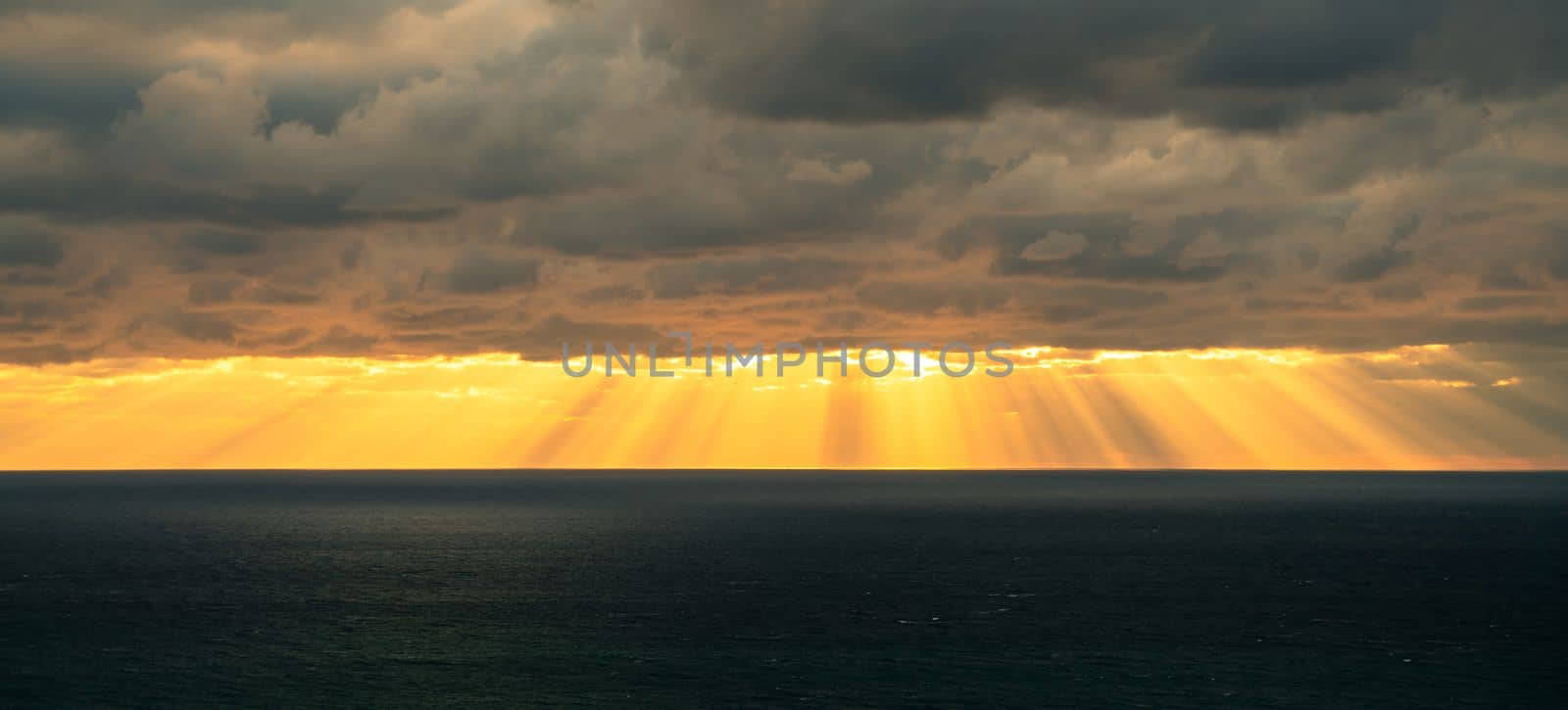 Sunbeams by the sea of clouds baner. Seascape with dark clouds and the rays of the sun from them. by Matiunina