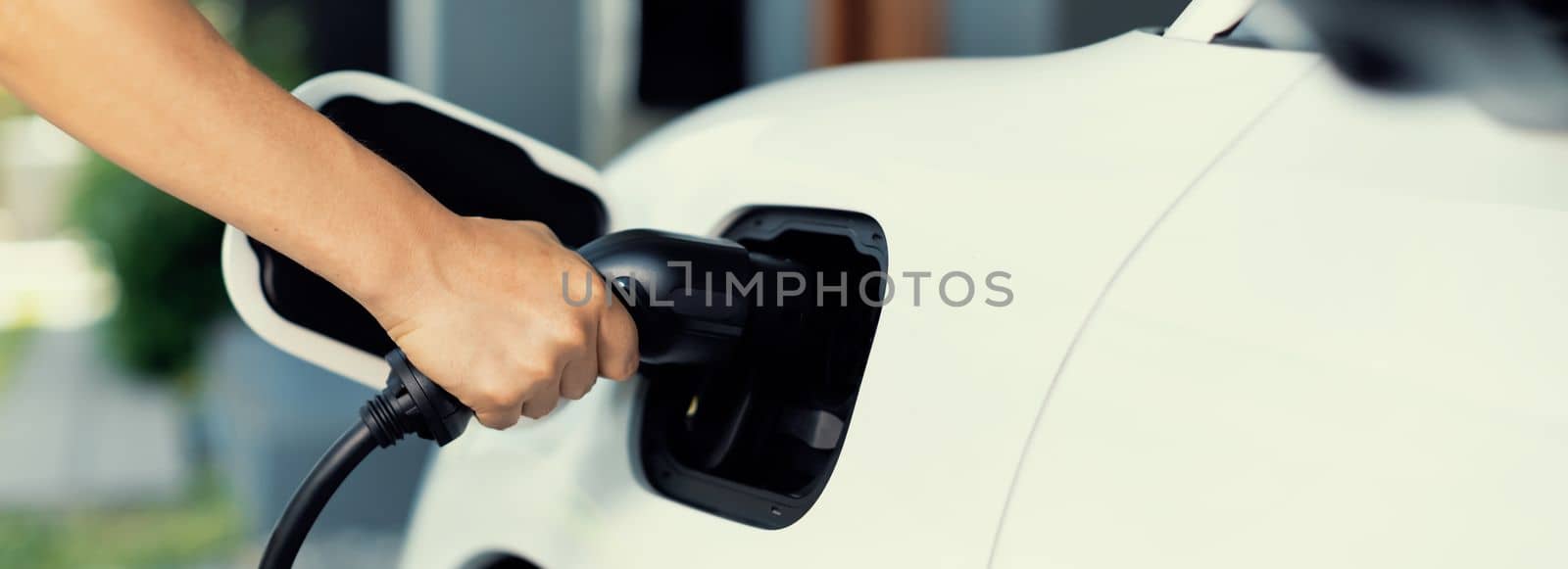 Progressive concept of hand insert an emission-free power connector to the battery of electric vehicle at home. Electric vehicle charging via cable from charging station to EV car battery