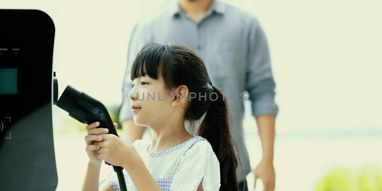 Focus image of progressive young girl holding EV charger device. by biancoblue