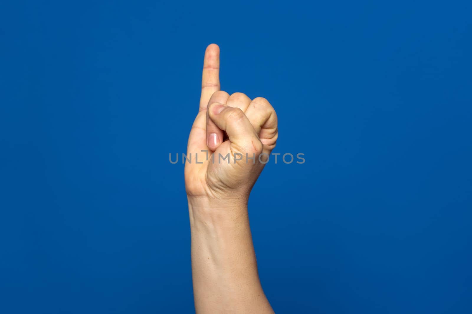 Man's hand with the little finger raised as a sign of promise or oath, isolated on blue background