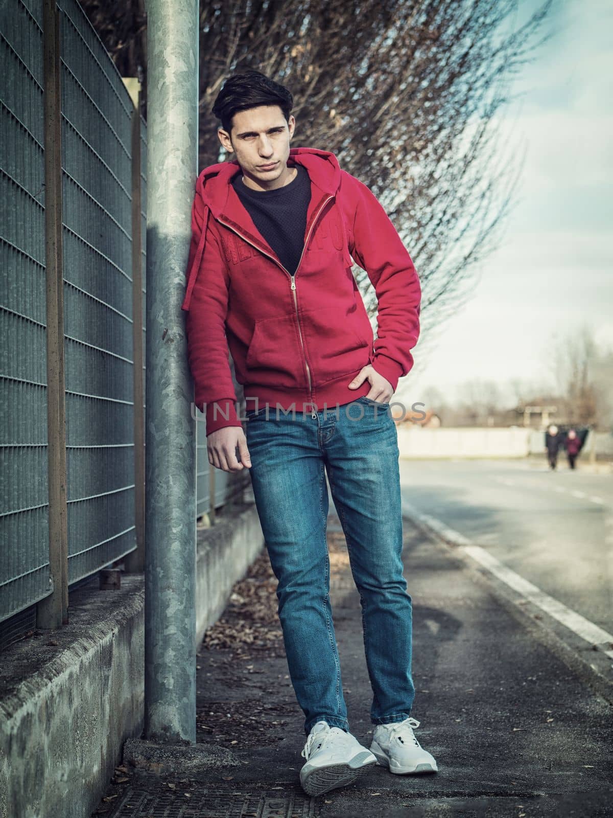 Attractive young man in city street leaning against pole by artofphoto