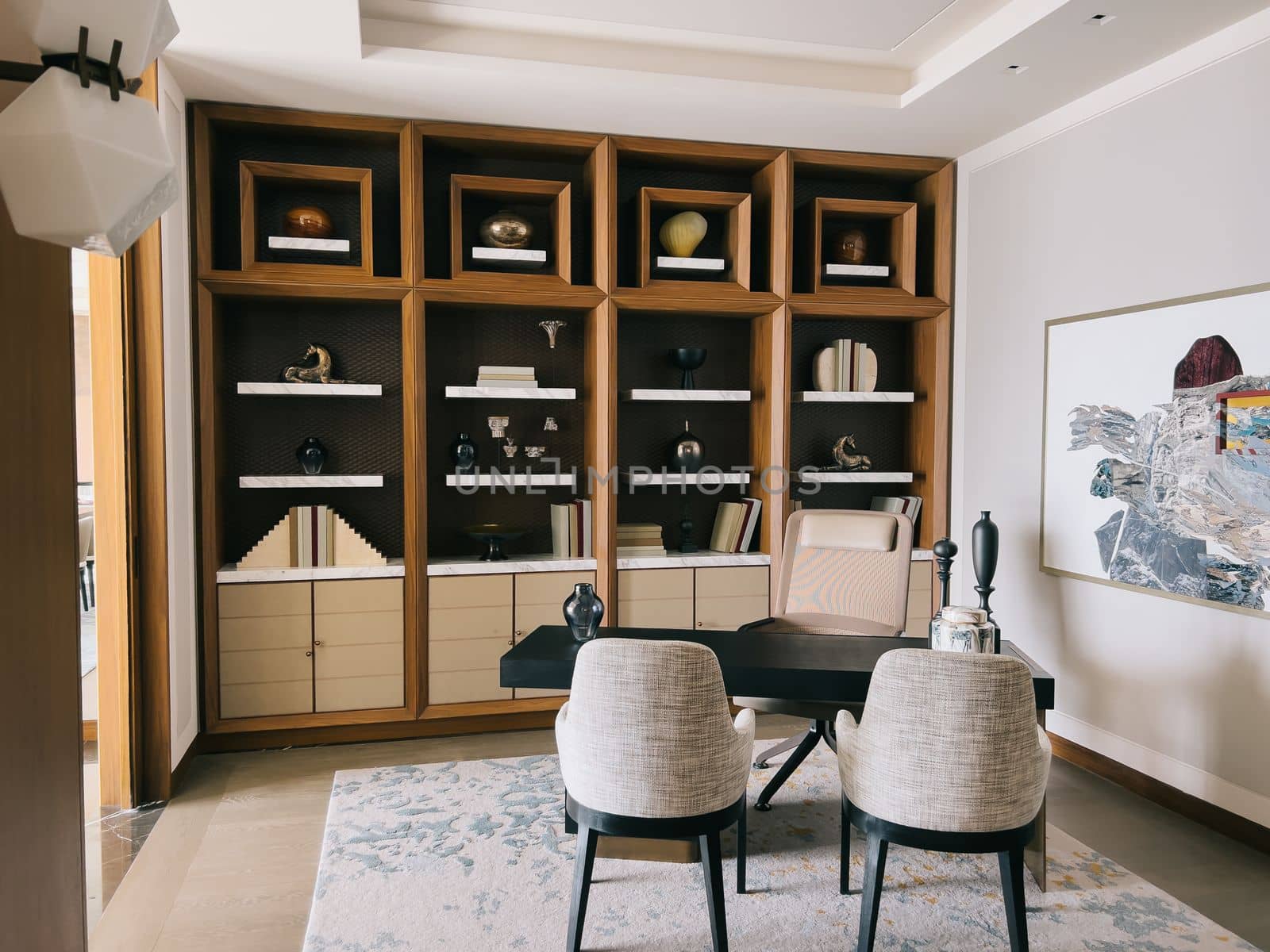 Wooden cabinet with shelves next to the table and armchair in the office of the hotel room. High quality photo