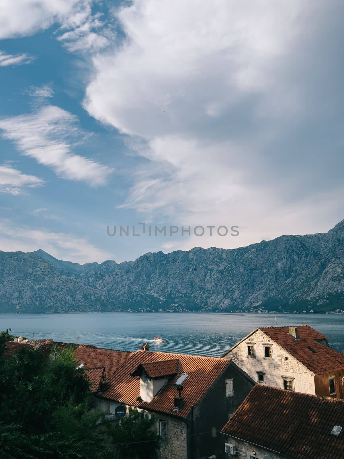 Sunbeams on the red tiled roofs of houses on the shore of the Bay of Kotor. High quality photo