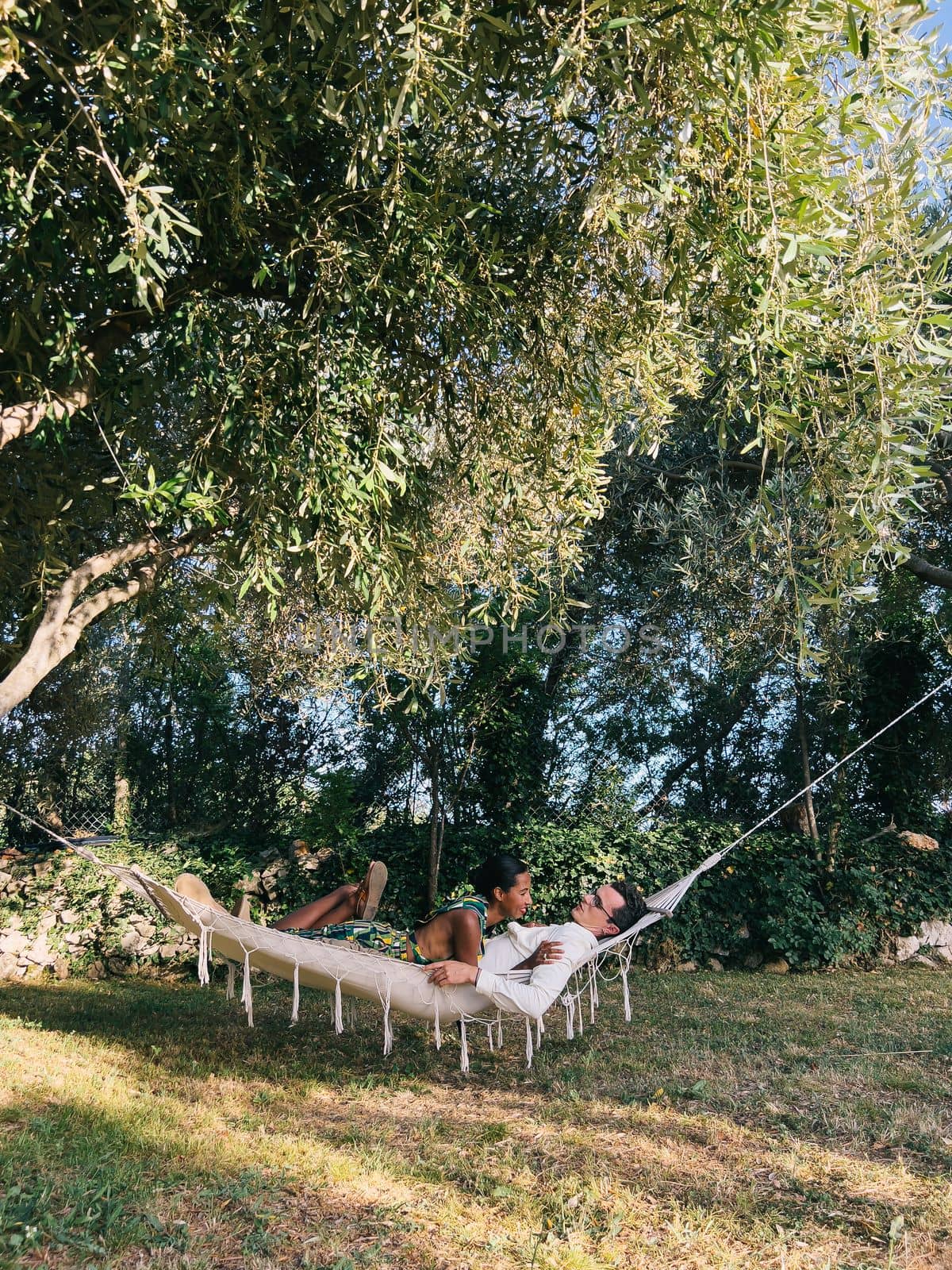 Smiling woman lying on man in hammock in garden. High quality photo