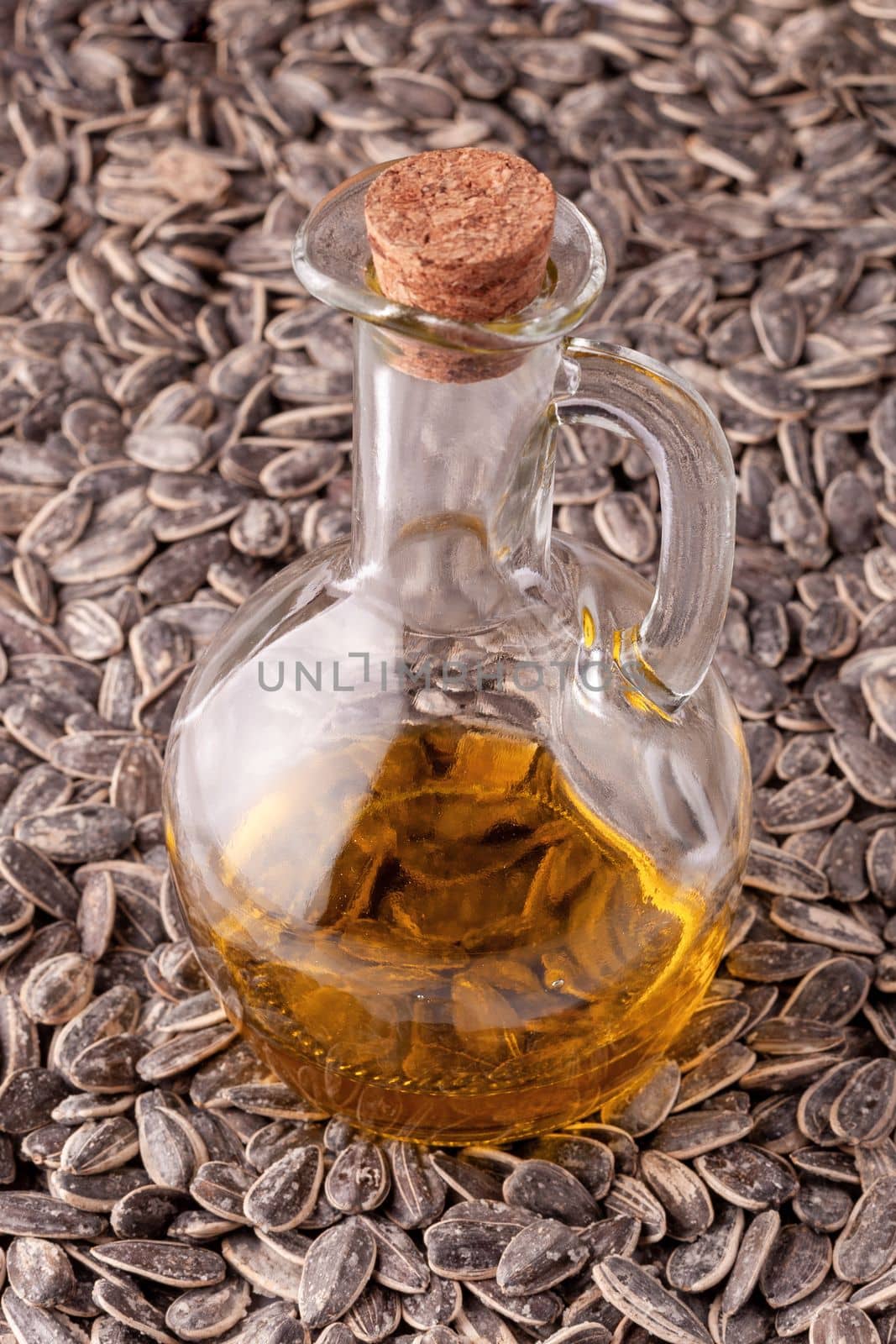glass pitcher of sunflower oil on the sunflower seeds, side view