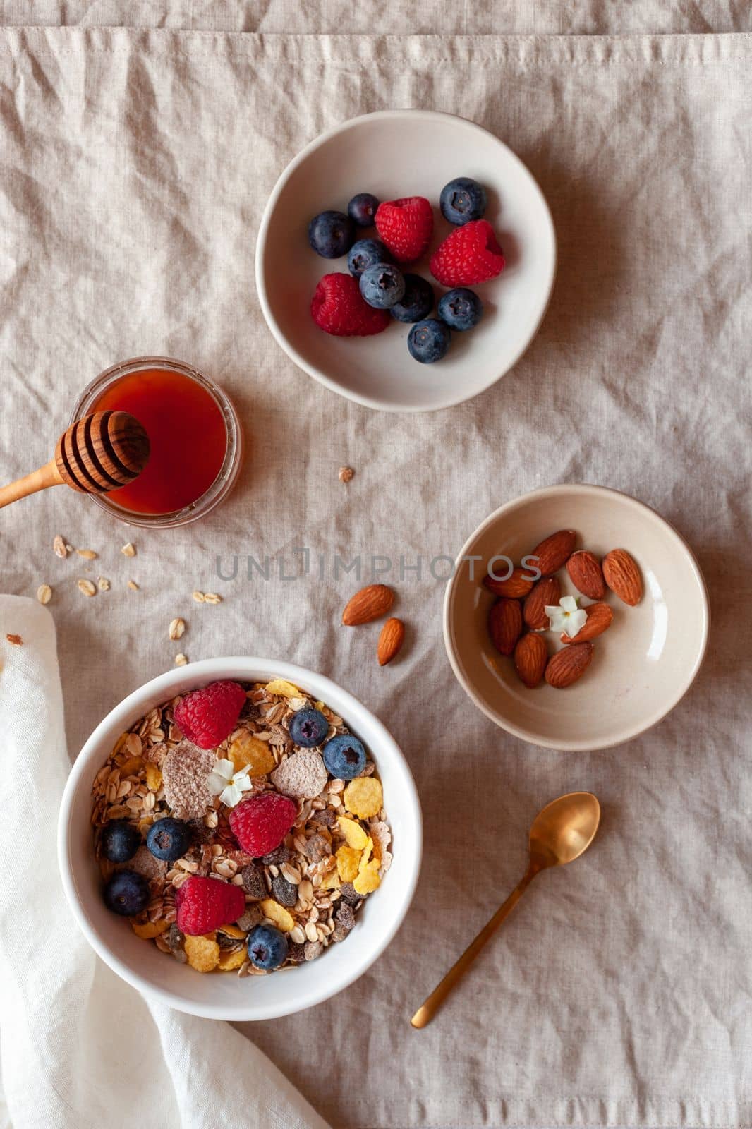 portion of morning breakfast of oat flakes, fresh berries, almonds and honey on the cotton table-cloth, top view