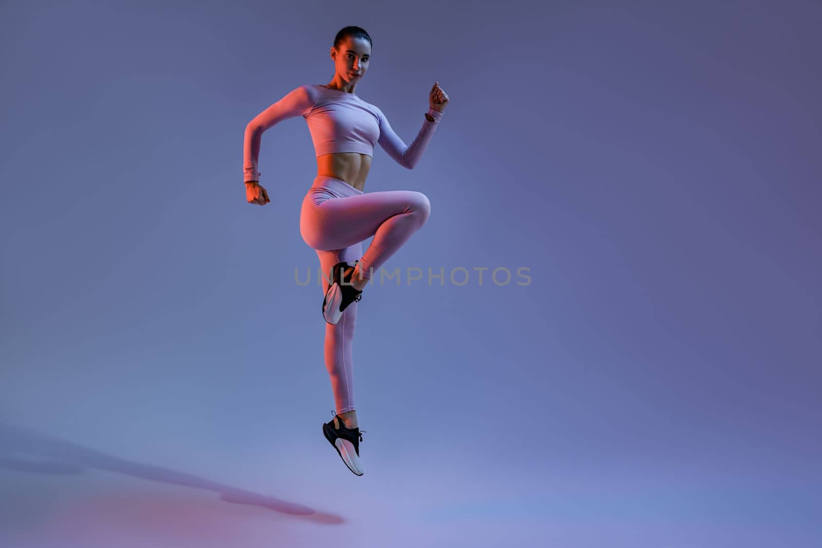 Sporty woman in sportswear jumping on studio background. Sport and healthy lifestyle by Yaroslav_astakhov