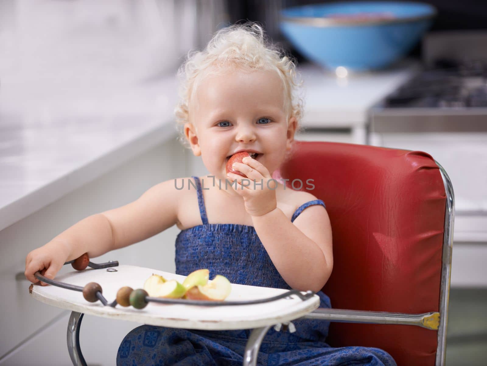Biting into that apple. A cute baby girl with curly hair biting into an apple
