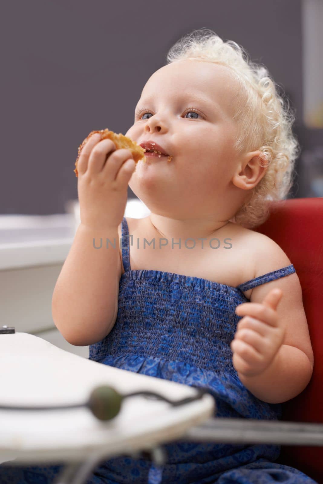 BAby is hungry. a cute young baby sitting in a high chair eating
