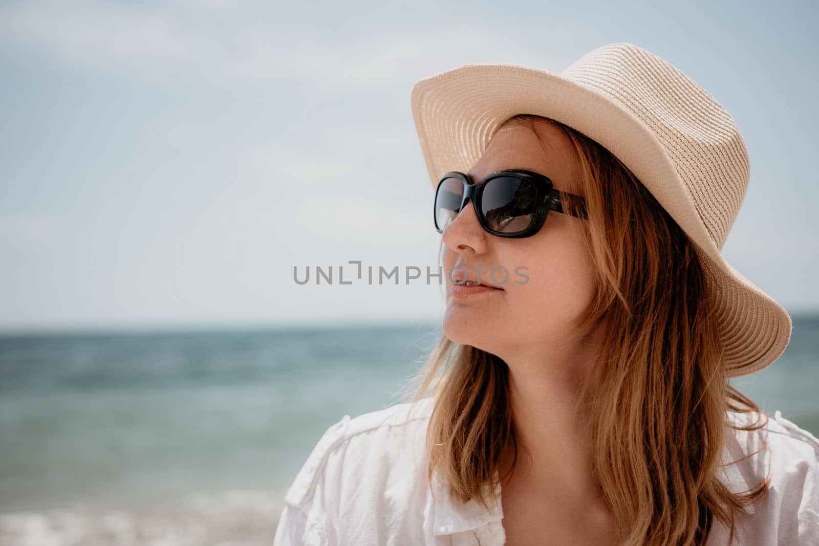 Young woman in red bikini on Beach. Blonde in sunglasses on pebble beach enjoying sun. Happy lady in one piece red swimsuit relaxing and sunbathing by turquoise sea ocean on hot summer day. Close up,