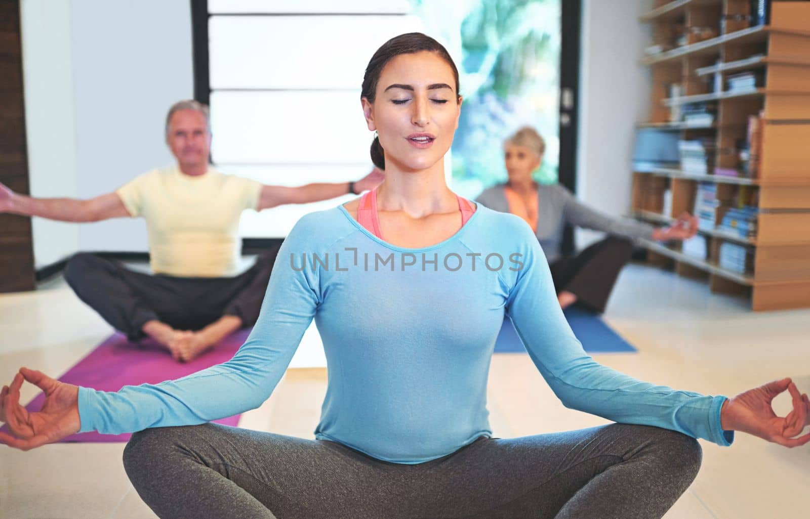 Free your body of any tension. a yoga instructor guiding a senior couple in a yoga class. by YuriArcurs