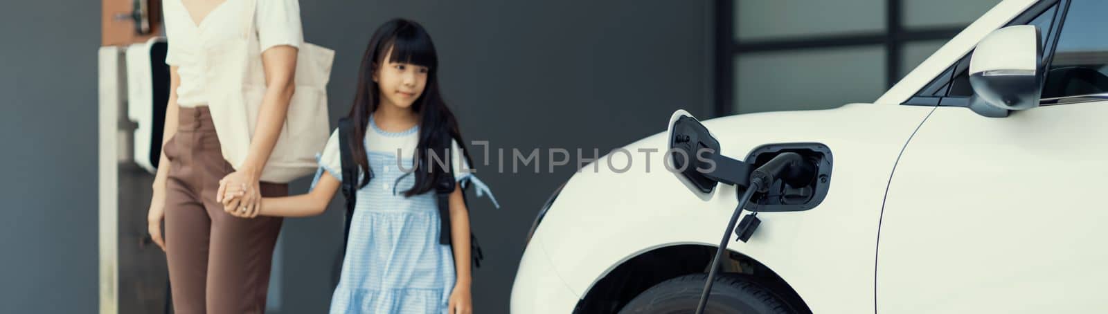 Progressive lifestyle of mother and daughter with EV car and charging station. by biancoblue