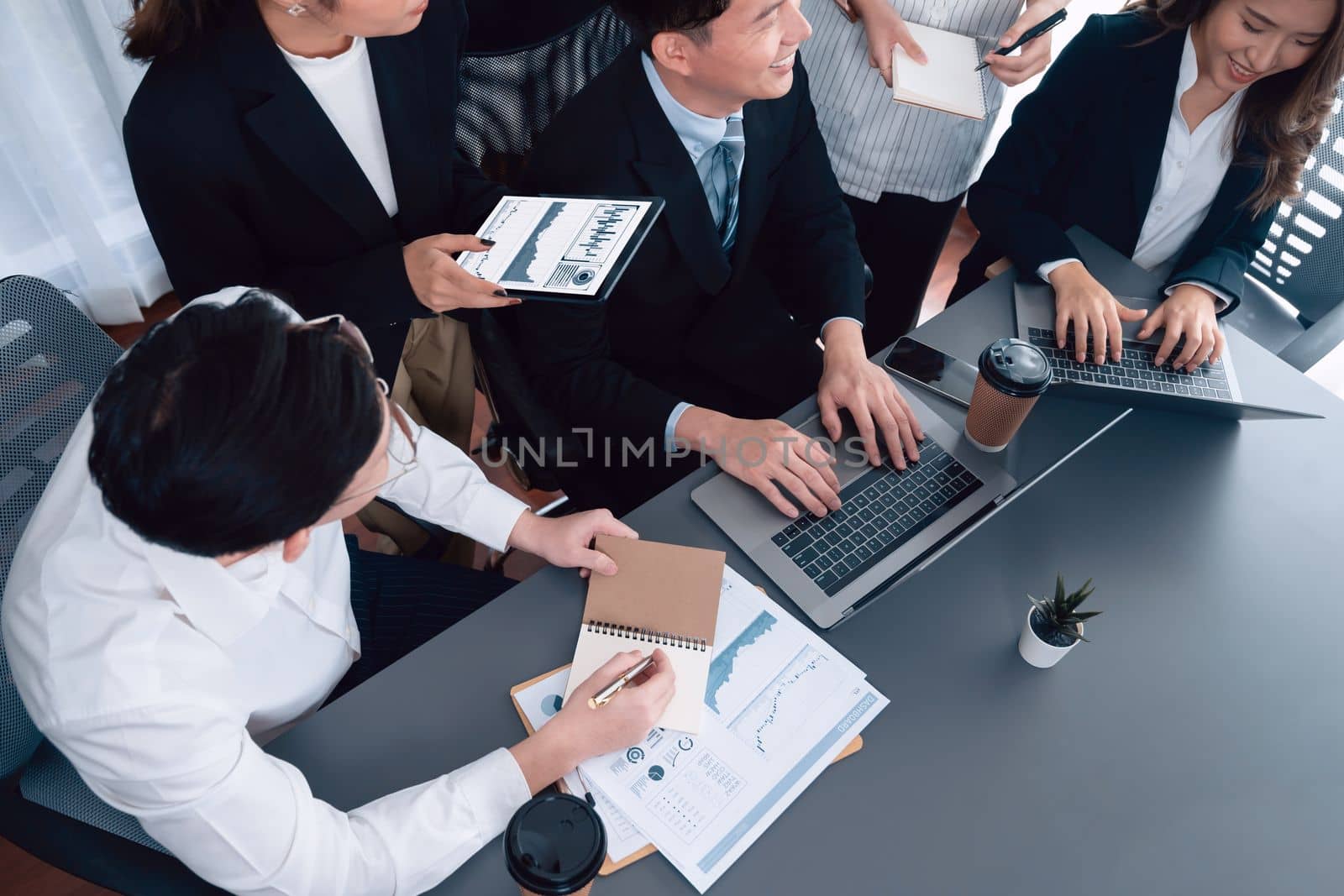 Harmony in office concept as business people analyzing dashboard paper together in workplace. Young colleagues give ideas at manager desk for discussion or strategy planning about project.