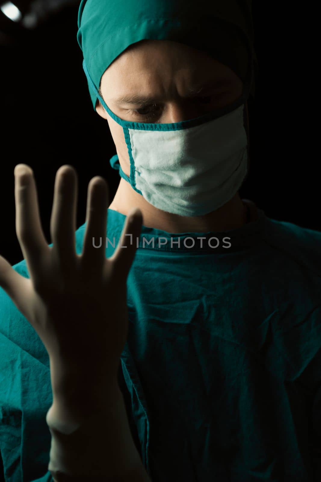 Surgeon put on protective surgical sterile glove and mask before perform surgery by biancoblue