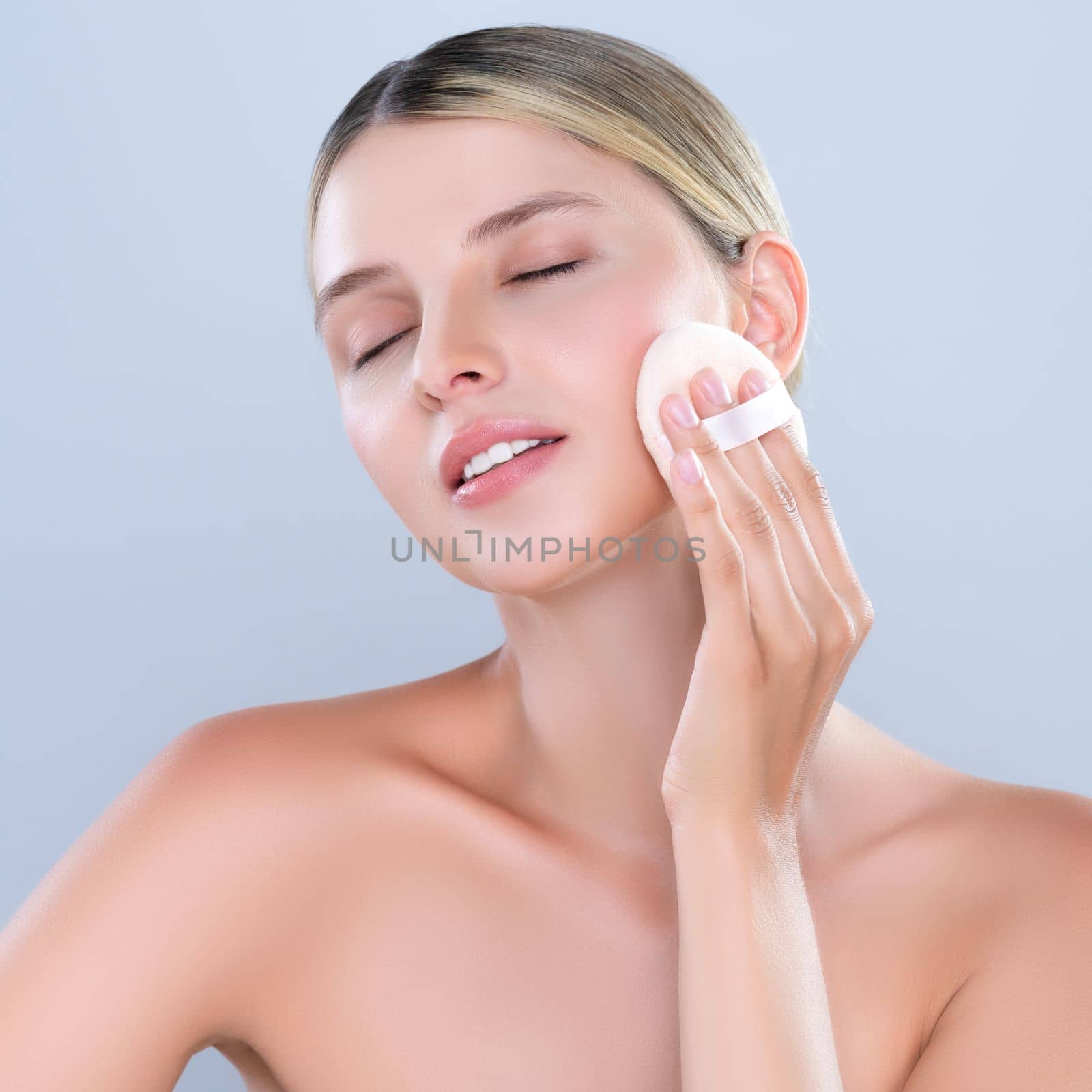 Alluring beautiful female model applying powder puff for facial makeup concept. by biancoblue