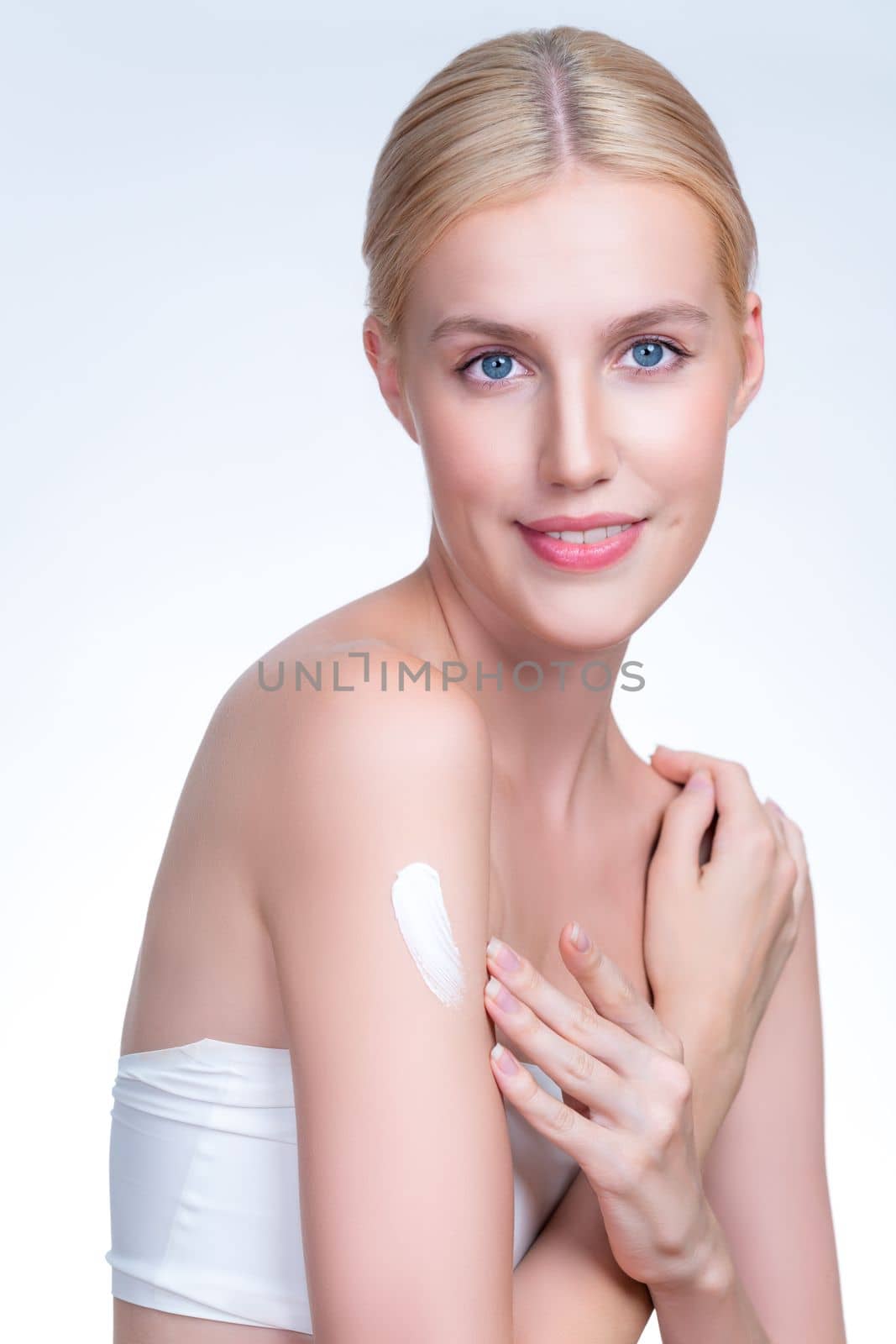 Personable beautiful woman putting skincare cream on isolated background. by biancoblue