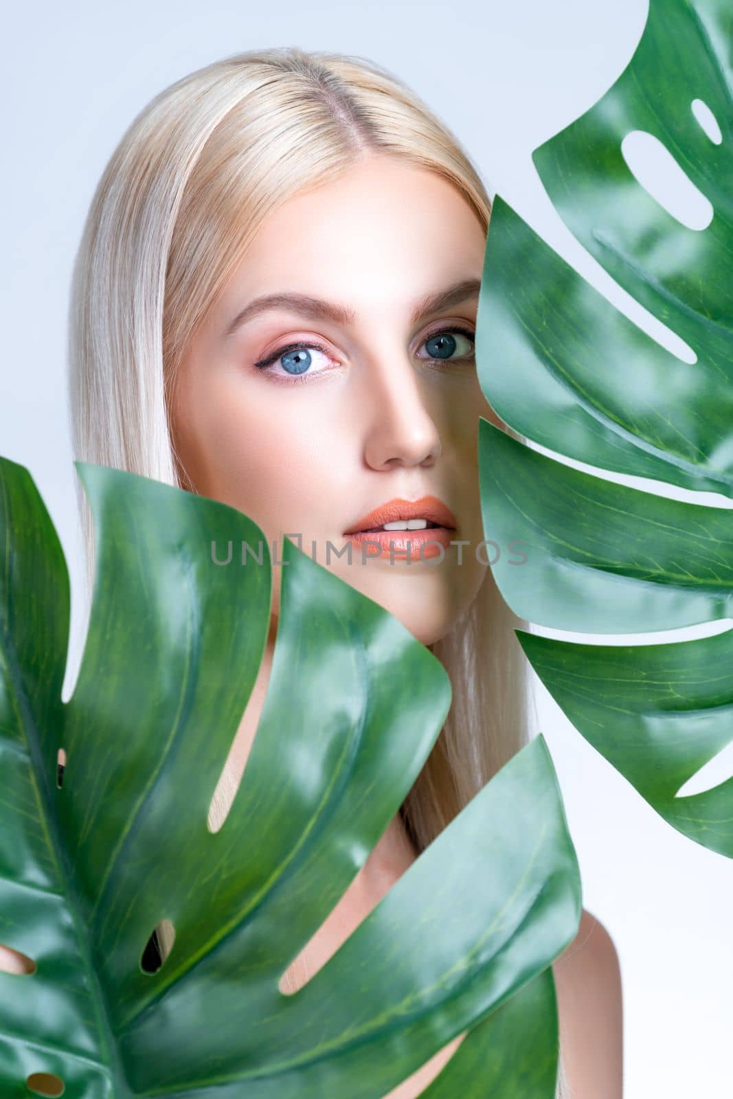Closeup facial portrait personable woman holding green monstera. by biancoblue